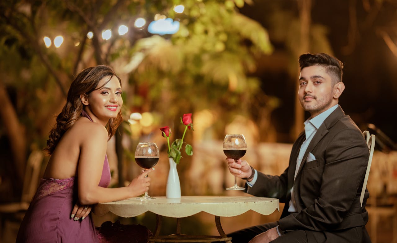 Home Elegant couple sharing a romantic evening with wine and roses at an outdoor setting.